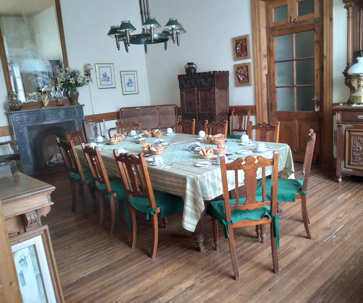 El comedor, con la mesa larga puesta para el desayuno, la chimenea y el aparador tallado.