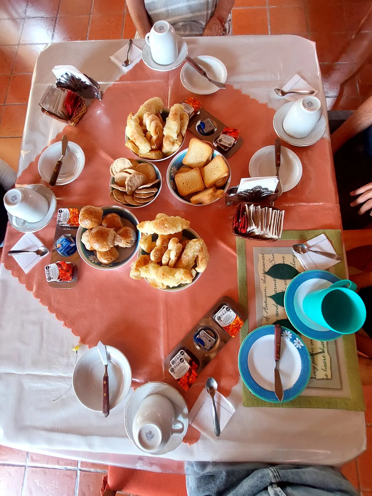 El desayuno servido en la mesa: medialunas, tostadas, café, mermeladas y manteca.