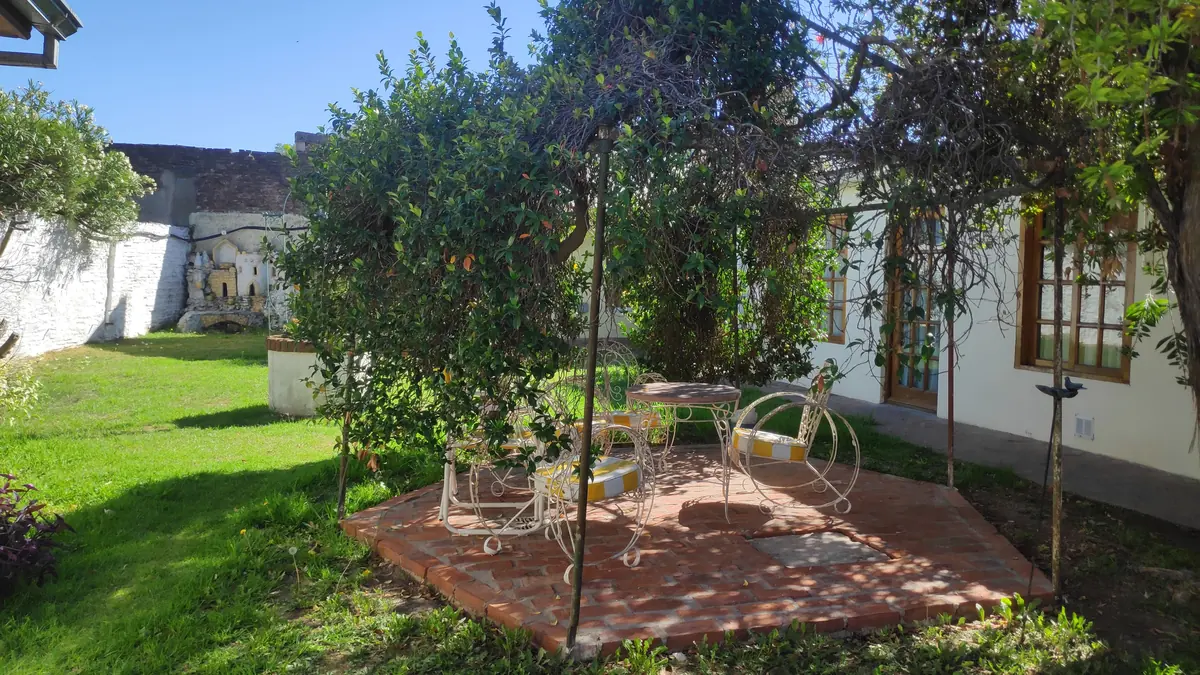 La glorieta del jardín, con sillas de hierro bajo los árboles.