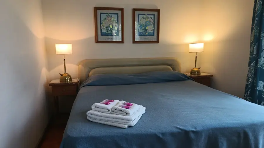 Habitación con acolchado azul y dos lámparas.