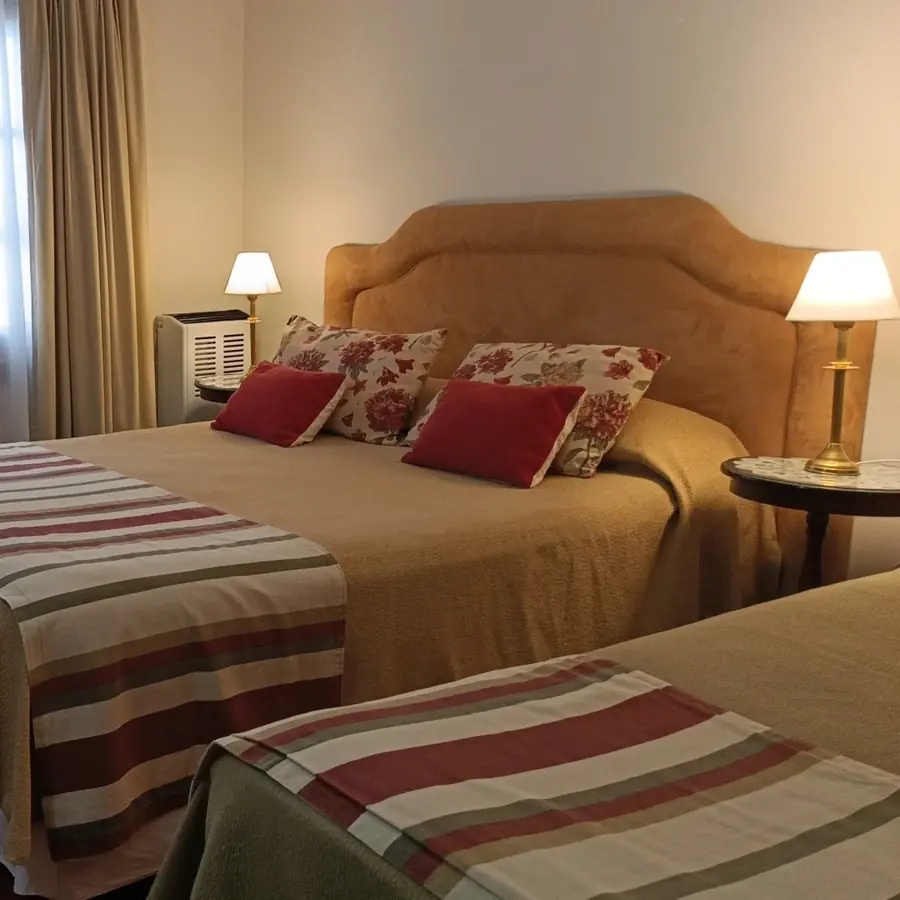 Una habitación con acolchados a rayas y la luz de la ventana.