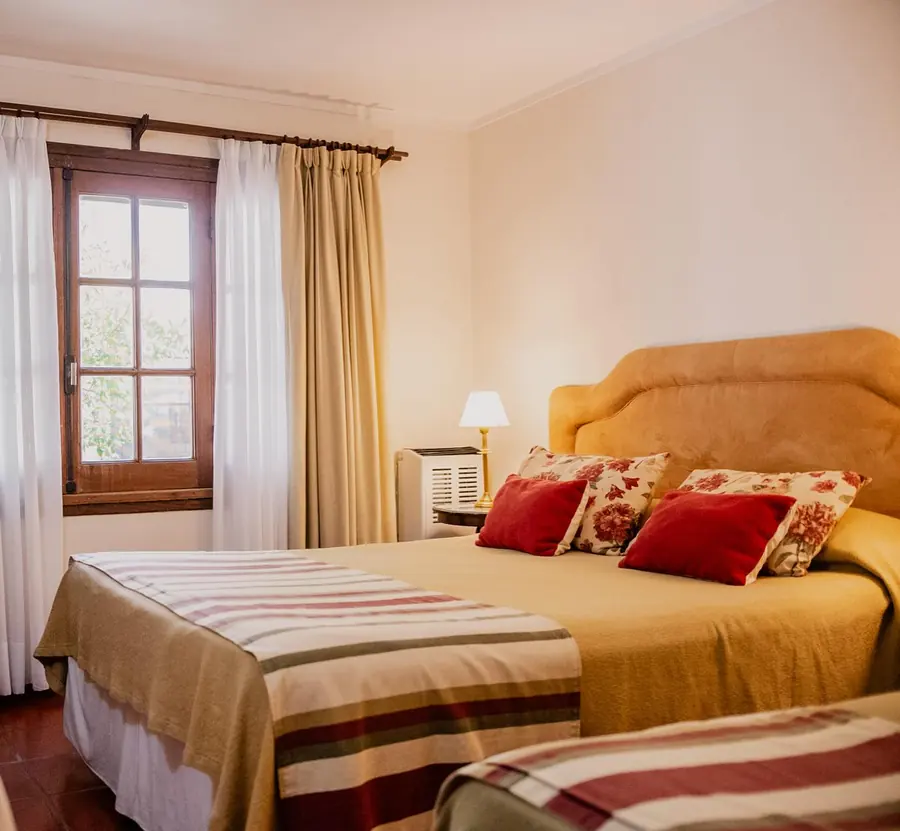 Habitación triple, con una cama matrimonial y una individual con acolchados a rayas.