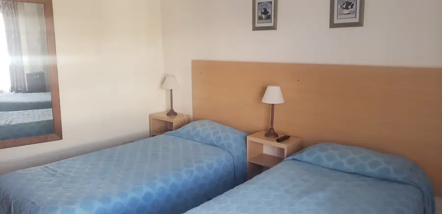 Habitación con dos camas individuales y acolchados celestes.